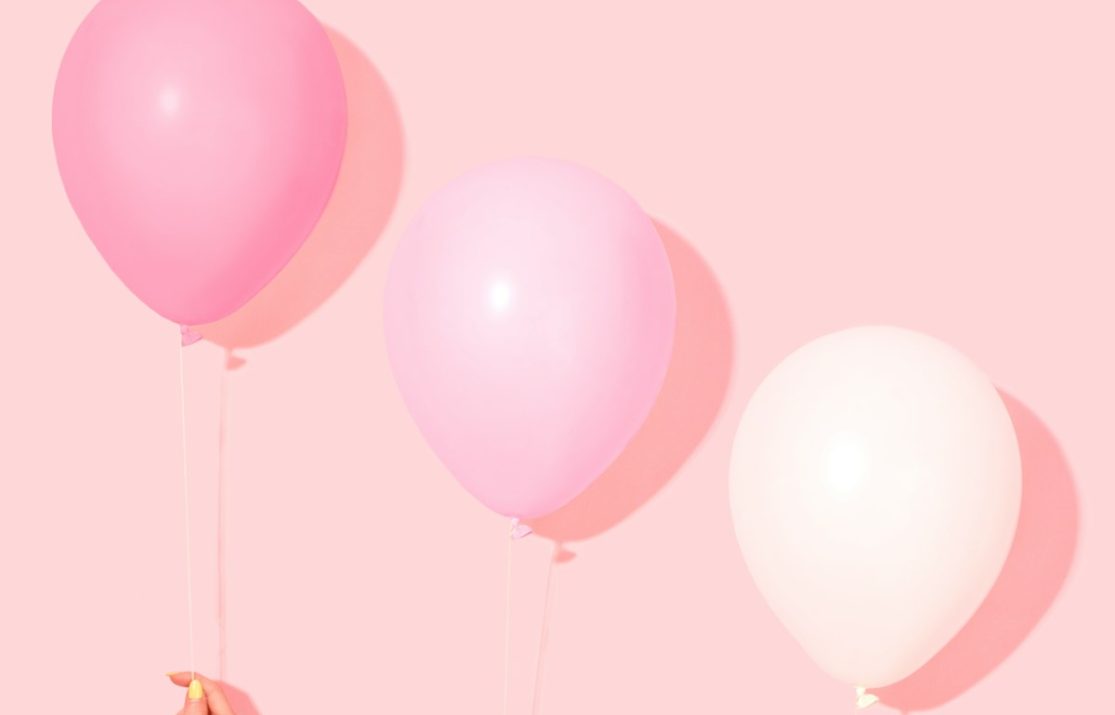 person holding pink and white balloon